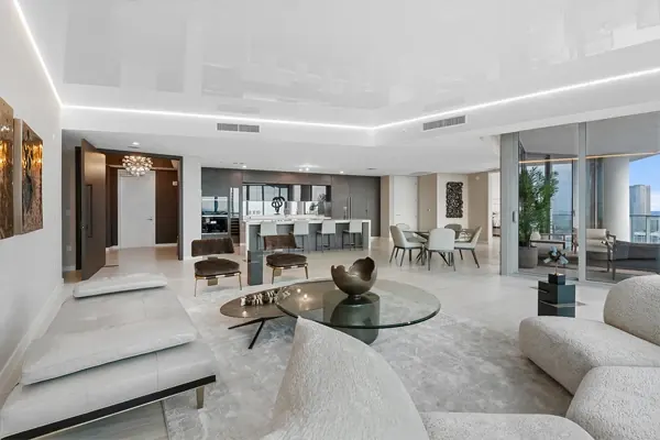 Penthouse living room with white furnishings and glass doors to a city-view balcony