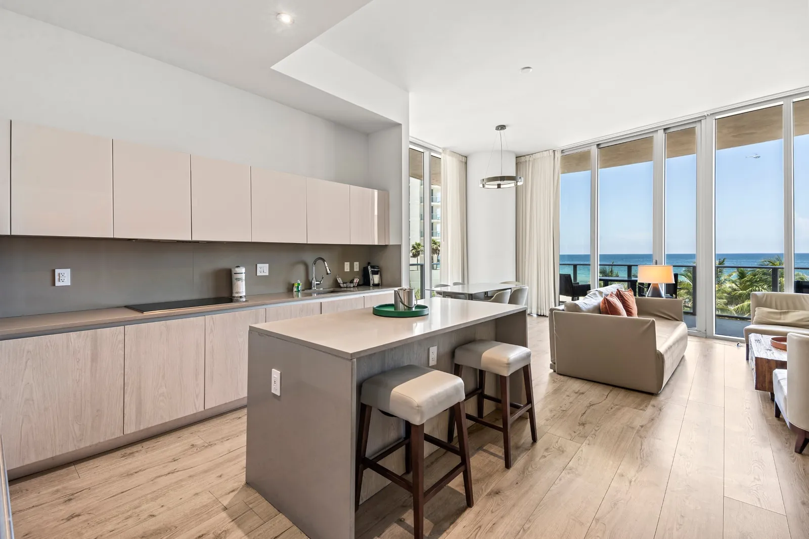 Open kitchen and living room with floor-to-ceiling windows overlooking the ocean in Hallandale Beach